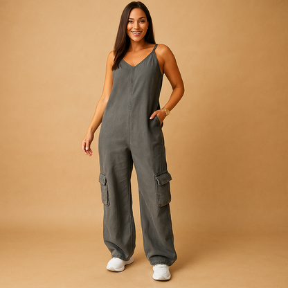 Woman wearing a high-waisted denim V-neck jumpsuit with an open back and crossed straps, ideal for festivals, summer days, and casual outings.
