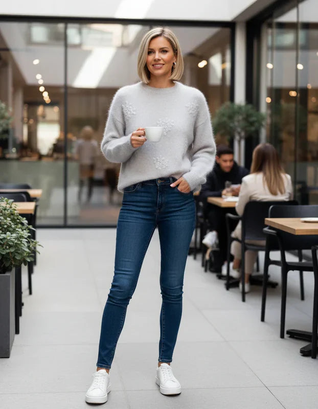 Woman holding a cup in an indoor setting with tables and chairs.